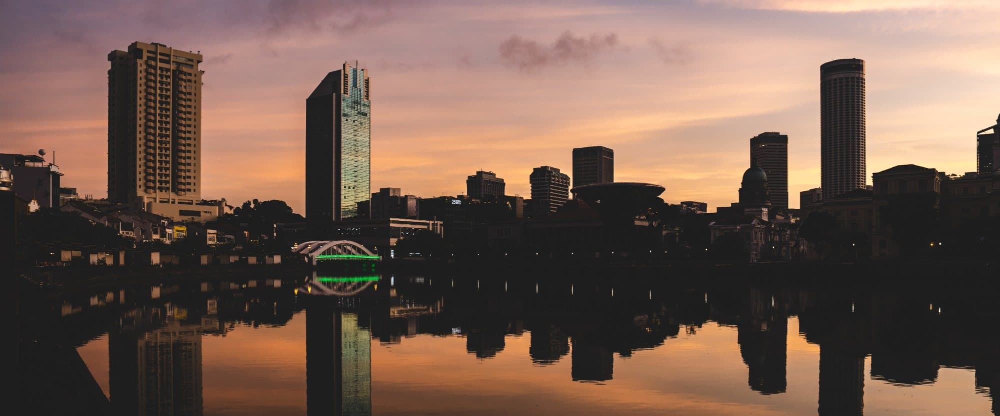 A city skyline and its reflection in still water at dusk